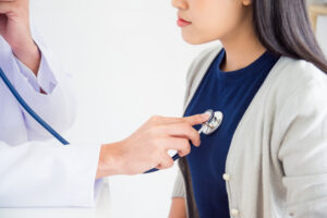 Doctor checking patient's heartbeat by stethoscope at hospital