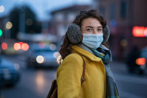 Woman wearing a face mask and thick clothing during Winter