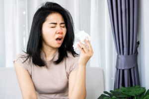 woman sneezing and holding paper tissue 